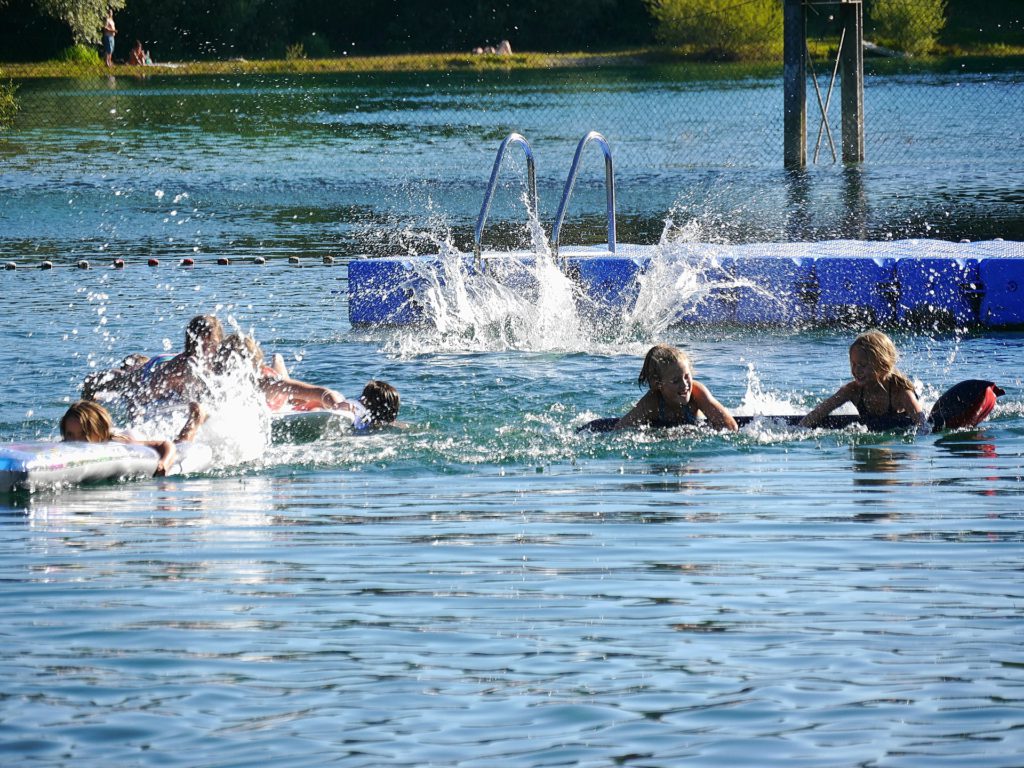 Några barn som plaskar och badar i en sjö.
